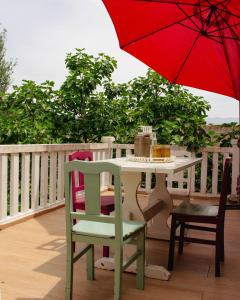 une table, des chaises et un parasol rouge sur une terrasse dans l'établissement Casa das Fontes, à Ponte da Barca