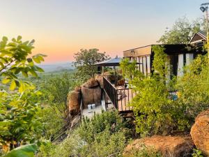 a house on the side of a hill with trees at Makgobelo Lodge-The Glass House- Solar powered in Ga-Mokalapa