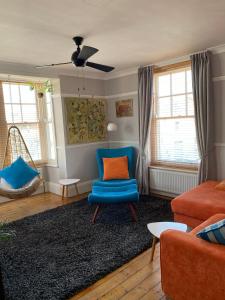 a living room with a blue chair and a couch at Herne Bay Central - 2 minutes from beach apartment in Herne Bay