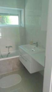 une salle de bain blanche avec une baignoire et un lavabo dans l'établissement Holiday home in Balatonkeresztur 44078, à Balatonkeresztúr
