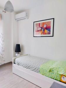una camera bianca con un letto e una foto appesa al muro di VISTAMARE apartments Reggio Calabria a Reggio di Calabria