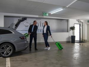 a man and woman standing next to a car with a suitcase at Central Hotel in Villingen-Schwenningen