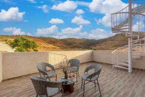 a balcony with chairs and a table with a view at ELIVAAS Shourya Zenna Luxe 3BHK Villa with Pvt Pool, Udaipur in Udaipur