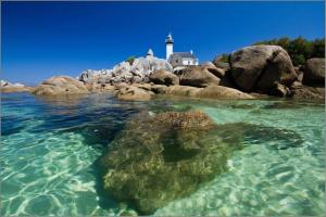 a lighthouse on a rocky island in the water at La Maison du Lividig 3 étoiles OT29 in Brignogan-Plages