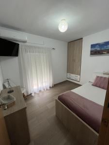 een slaapkamer met een bed, een wastafel en een televisie bij CASA GODOY in Cáceres