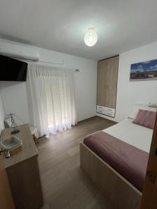 a bedroom with a bed and a sink and a television at CASA GODOY in Cáceres