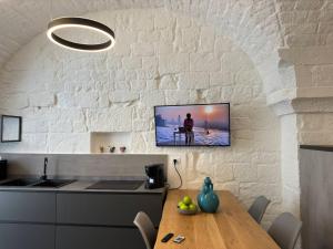 Una cocina con una mesa y un televisor en la pared. en Star White, en Ostuni 10 fotos más