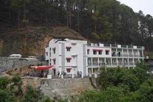 a large white building on a hill next to a mountain at Pine hills resort and restaurant in Barkot