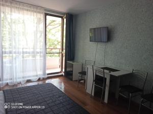 a room with a table and chairs and a television at Студио Илана in Shkorpilovtsi