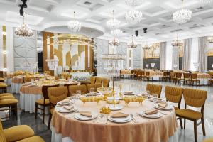 a banquet hall with tables and chairs and chandeliers at Diamond Hotel Shymkent in Shymkent