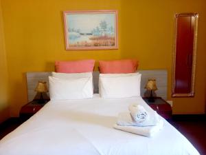 um quarto com uma cama branca com uma toalha em G&G Guesthouse em Joanesburgo