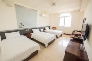 una camera d'albergo con due letti e una TV a schermo piatto di Taijing Hotel a Beigan