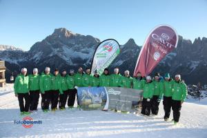 a group of people in green jackets standing in the snow at Villa Speronella in San Martino di Castrozza