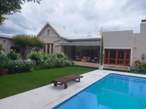 a swimming pool with a bench next to a house at Oaktree in Burgersdorp
