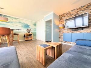 ein Wohnzimmer mit einem Sofa und einem TV an einer Backsteinwand in der Unterkunft Ferienpark Sierksdorf App 111 - Strandlage in Sierksdorf