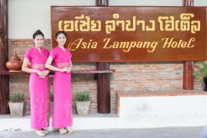 Due donne sono in piedi davanti a un cartello di Asia Lampang Hotel a Lampang