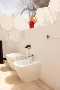 a white bathroom with a sink and a toilet at Folià - Natural Experience in San Vito dei Normanni