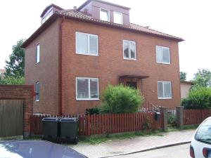 une maison en briques rouges avec une clôture devant elle dans l'établissement Honeymoon Guesthouse, à Helsingborg