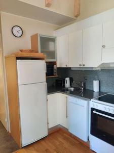 a kitchen with white appliances and a clock on the wall at Kylpyla Spa, Saimaa Villa Efrat B8 in Imatra