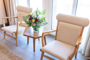 two chairs and a table with a vase of flowers at Beach Walk Boutique Jumeirah in Dubai