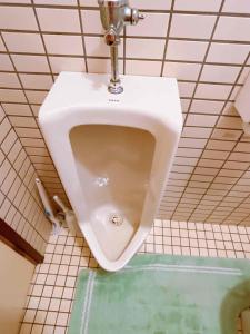 a white urinal in a bathroom with a tiled wall at T&T Fujiyama Guest House in Fujiyoshida