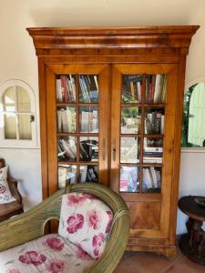 a wooden book cabinet with glass doors and a chair at Orangerie in Bonnieux