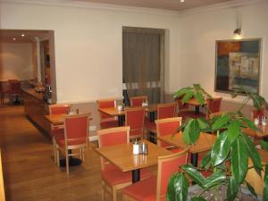 a restaurant with tables and chairs and a plant at Americana Hotel in London