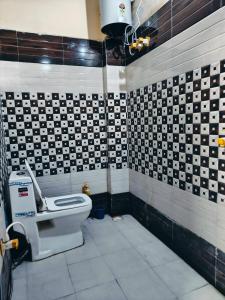 a bathroom with a toilet and black and white tiles at New Gayatri Palace Near Prem Mandir in Vrindāvan