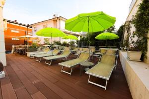 a group of tables and chairs with green umbrellas at Hotel Villa Anthea in Garda