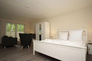 ein Schlafzimmer mit einem weißen Bett und einem Stuhl in der Unterkunft Ferienhaus Inselhus Haus - Terrasse, Garten in Glowe