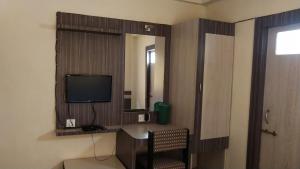 a room with a television and a desk with a chair at Hotel Vaishali in Nashik