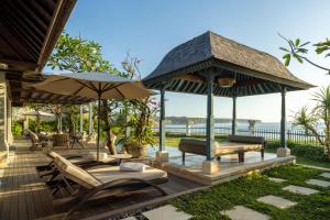 a deck with a gazebo and chairs and tables at Jumeirah Bali in Uluwatu