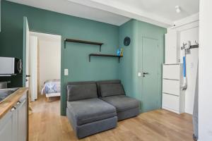 a living room with a couch and a blue wall at 9-minute walk from La Défense - 1 bedroom in Courbevoie