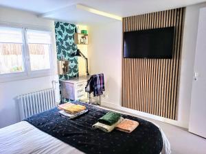 a bedroom with a bed with a tv on the wall at La Fremille T2 - 1br - 400m gare Versailles Paris - Piscine Terrasse Parking in Saint-Cyr-lʼÉcole