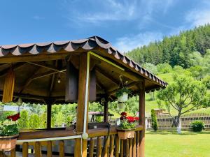 a wooden gazebo with flowers in a yard at Căsuțe Poiana Largului in Poiana Largului +19 photos
