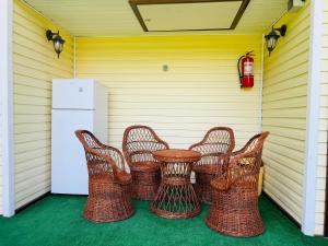 a patio with wicker chairs and a table and a refrigerator at Căsuțe Poiana Largului in Poiana Largului
