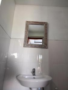 une salle de bain avec un lavabo et un miroir au mur dans l'établissement Batur Volcano Cottage, à Kubupenlokan