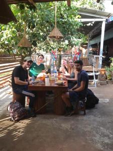 eine Gruppe von Menschen, die um einen Holztisch sitzen in der Unterkunft Happy Homestay Banlung & Trekking in Banlung