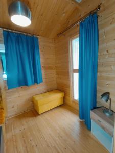una habitación con cortinas azules en una cabaña de madera en Zofia, en Grzybowo