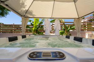 a remote control in a hot tub with an umbrella at Modular Bungalows With Heated Pool Artemis Greece in Artemida
