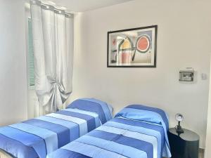 two blue beds in a room with a window at Alloggio Nala 6 in Biella