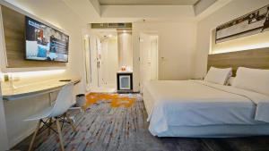 Dormitorio con cama, escritorio y TV en HARRIS Suites fx Sudirman, en Yakarta