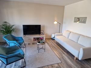 a living room with a couch and two chairs and a tv at Moderne Wohnung mit Sauna in Zülpich