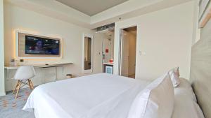 1 dormitorio blanco con 1 cama grande y TV en HARRIS Suites fx Sudirman, en Yakarta