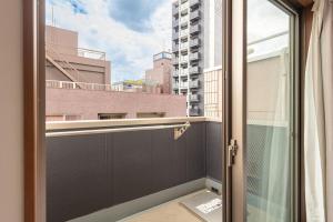 an open door to a balcony with a view of a building at Komachi Hotel Nipponbashi in Osaka