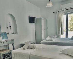 a bedroom with two beds and a desk and a tv at Nostos Studios in Parikia