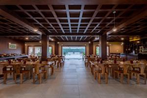 a dining room with wooden tables and chairs at River Bank Jungle Resort, Chitwan in Bharatpur