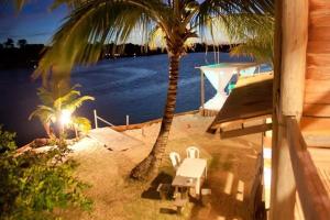 a beach with a table and a palm tree and a boat at Pôr do Sol Eco Suítes in Barra Grande