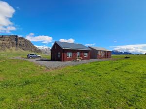 a house in a field with a car parked next to it at The Forgotten Farmhouse in Skogar