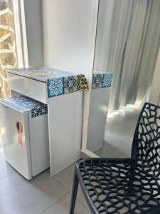 a chair next to a refrigerator and a table at Praia dos Anjos Suítes in Arraial do Cabo